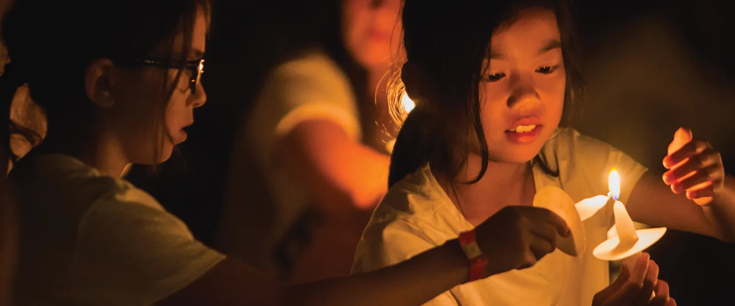 girls lighting candles for night meeting