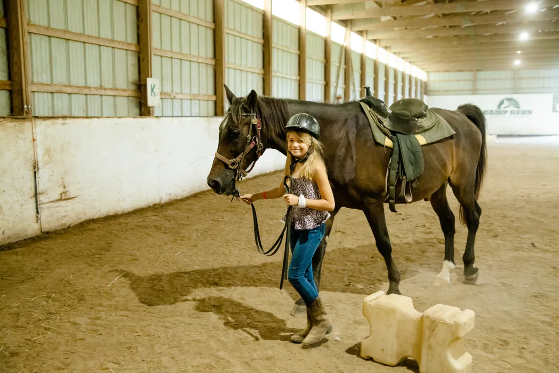 A girl walking with a horse at camp